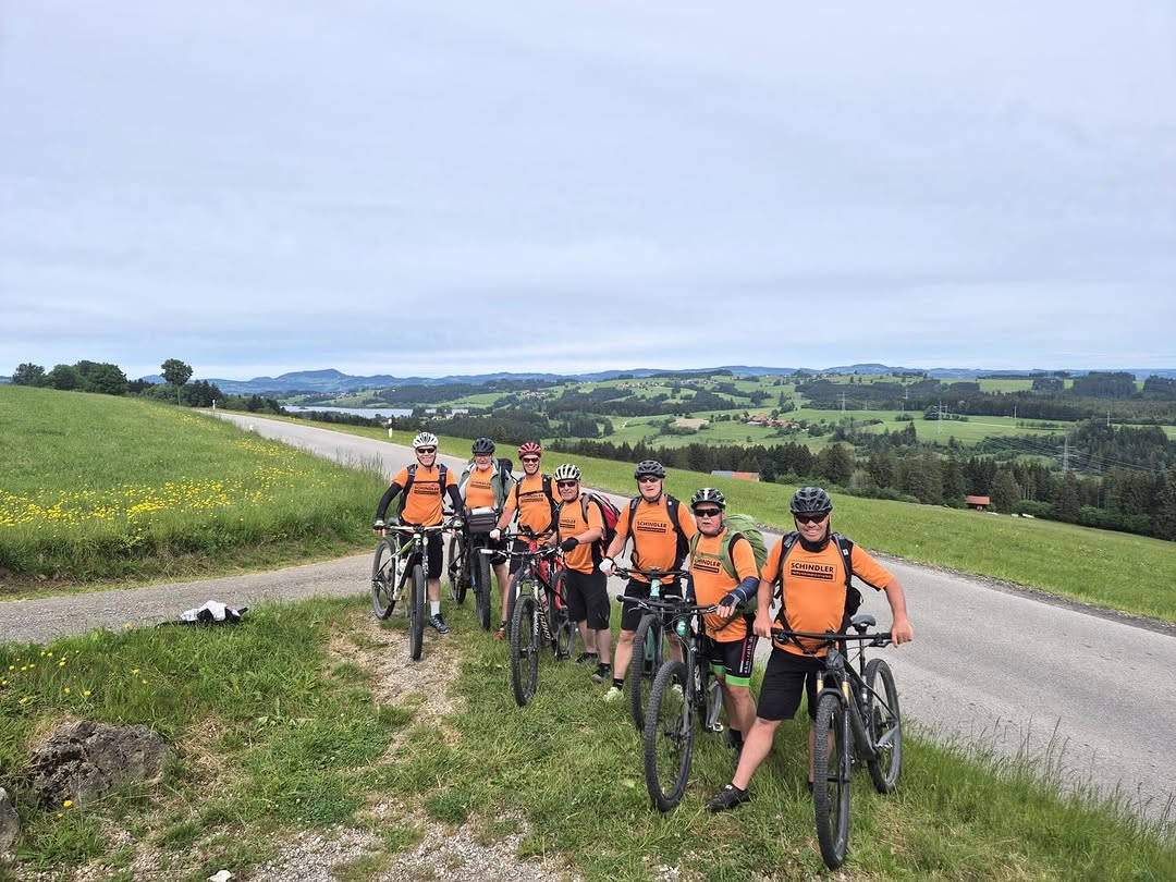 Das Schindler-Team in orangen Trikots auf einer Radtour vom Königssee nach Lindau